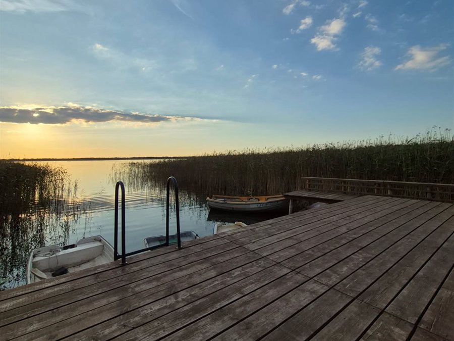 Pomost i łódki nad jeziorem o zachodzie słońca